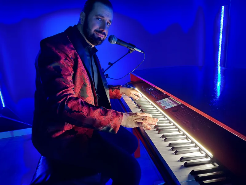 REYES al piano rojo y a la voz, con chaqueta roja y negra.