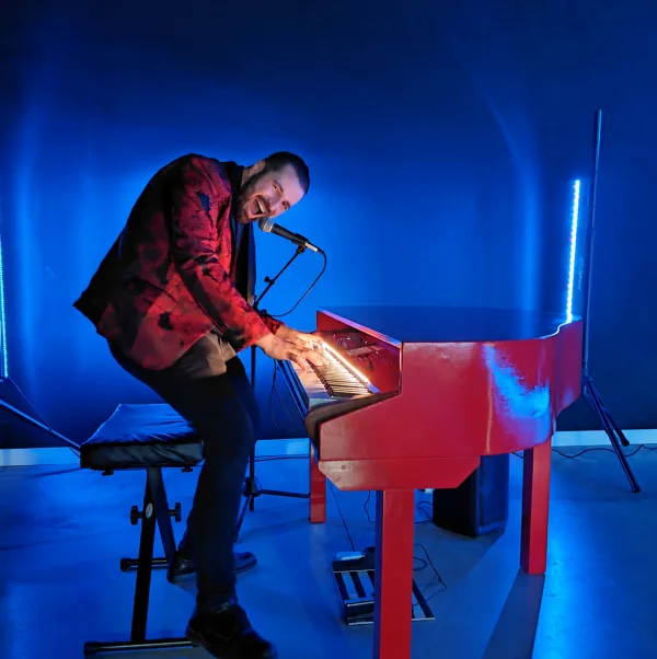REYES interpretando al piano rojo, con una puesta en escena llena de energía.